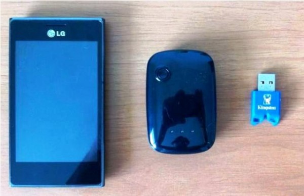 Comparativo de tamanho entre o rastreador (centro) e um pendrive (direita) e um celular (esquerda)